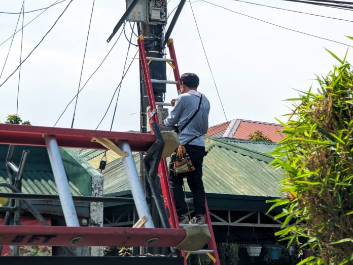 A technician troubleshoots a faulty internet fiber connection to a residence. Climbing up to check the outside junction box.